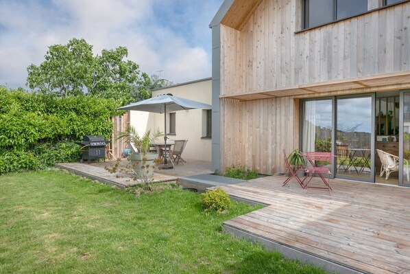 A modern house with a wooden deck, a barbecue area, and a glass door leading to an outdoor seating area. - Bright house with large terrace in La Roche-Bernard (La Roche-Bernard)