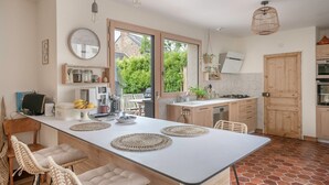 A modern kitchen with a central island, wooden cabinets, and a view of greenery outside. - Bright house with large terrace in La Roche-Bernard (La Roche-Bernard)