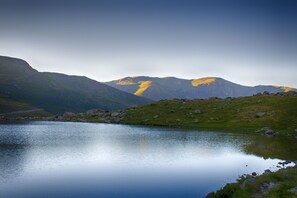 Um lago tranquilo rodeado por montanhas sob um céu claro.