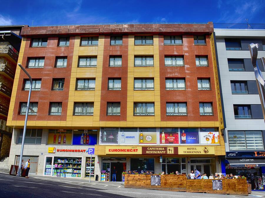 Ein mehrstöckiges Hotel mit gelbbrauner Fassade, mit einem Restaurant im Erdgeschoss und einem sichtbaren Hydranten.