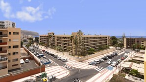 A multi-story building with a parking lot and a pedestrian crossing. - HomeForGuest Ático Cecilia con terraza y vistas al mar en Los Cristianos (Los Cristianos)