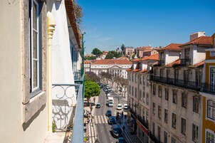 A street view with buildings, a clear sky, and parked cars.
