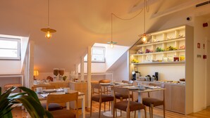 Een moderne keuken met witte kasten, een eethoek met houten stoelen en een plant op de voorgrond.