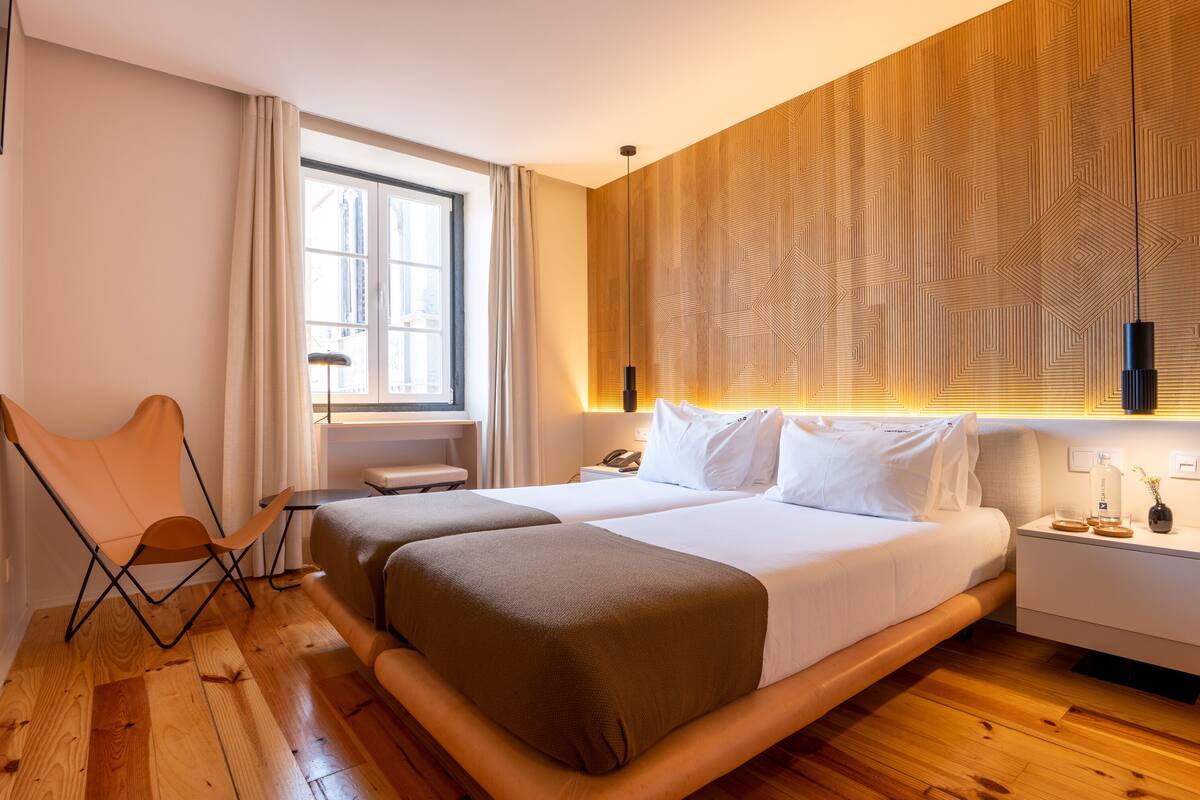 Een moderne hotelkamer met een groot bed, een houten vloer, een stoel en een raam met gordijnen.