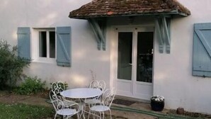 A white house with a tiled roof, a patio with white metal chairs, and a small garden area. - Maison Héouguère 29km from Dax and 15km from Orthez, and 5min from Amou (Castel-Sarrazin)
