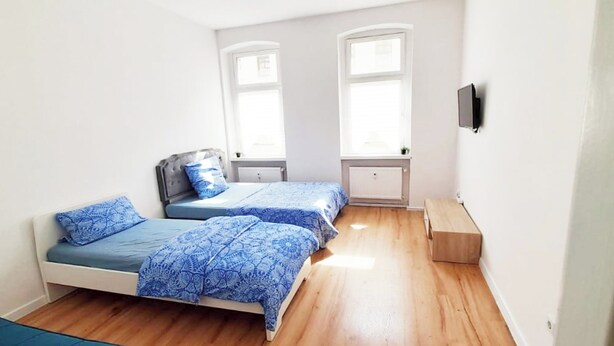 Une chambre avec deux lits, un plancher en bois et une fenêtre.