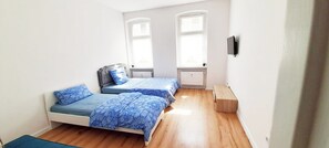 Une chambre avec deux lits, un plancher en bois et une fenêtre.