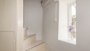 A staircase with white walls and a window with a stone wall view. - Kooky Cottage (Brecon)