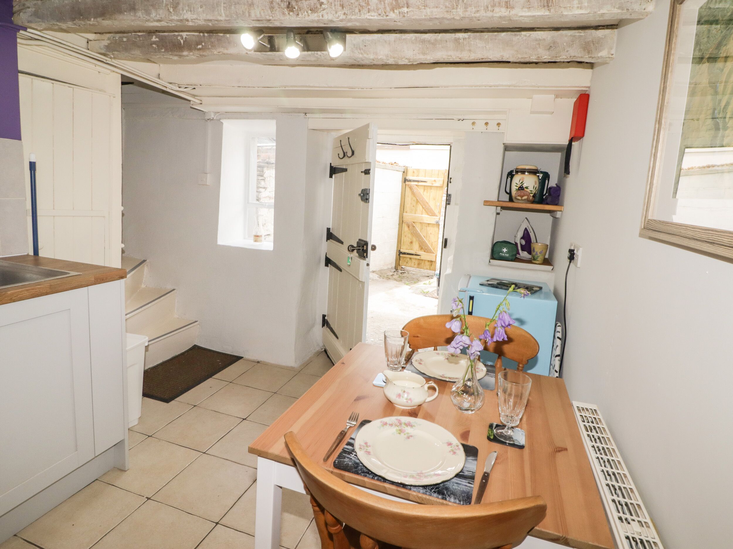 Una cocina con una mesa de comedor para dos personas, un fregadero y un ventanal.