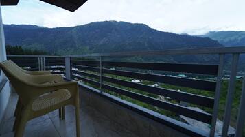 Un balcón con vistas a montañas y una silla.