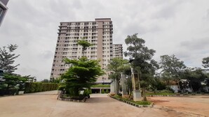 Un edificio residencial de varios pisos con un patio central, rodeado de follaje y árboles.