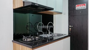 Una cocina moderna con estufa negra, pileta de acero inoxidable y armarios de madera.