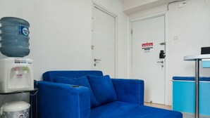 Ein blaues Sofa in einem Raum mit Wasserspender, Mülleimer und einer Tür mit Brandschutznachweis.