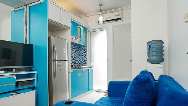 Ein gemütlicher Wohnbereich mit Küchenzeile, einem blauen Sofa und einem Fernseher.