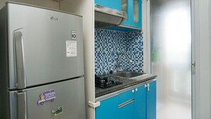 Eine kleine Küche mit Kühlschrank, Spüle und blauen Schränken.