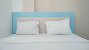 Ein Bett mit einem blauen Kopfteil und zwei weißen Kissen.