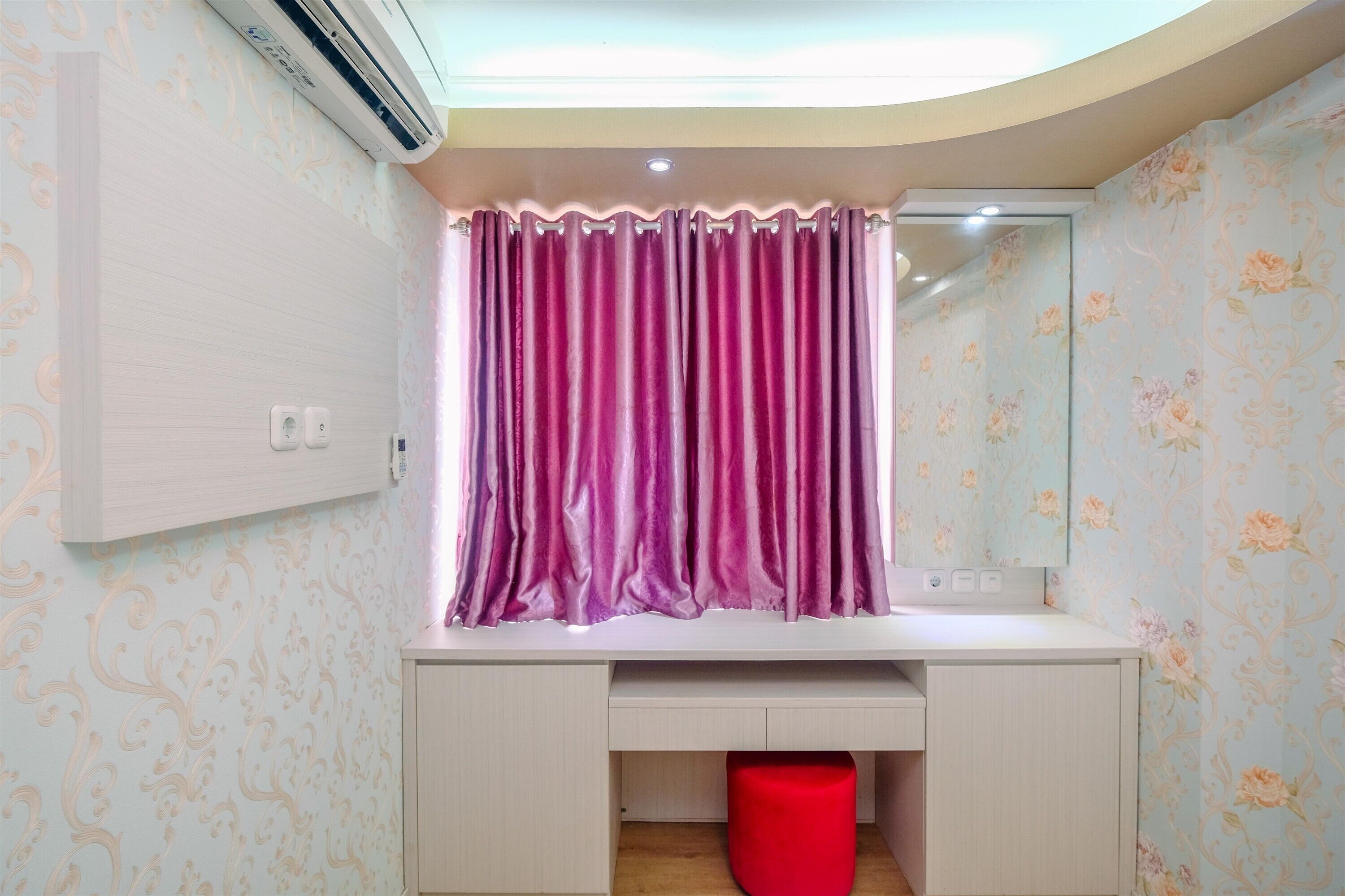 A bathroom with a vanity, a mirror, a red trash bin, and a purple curtain.