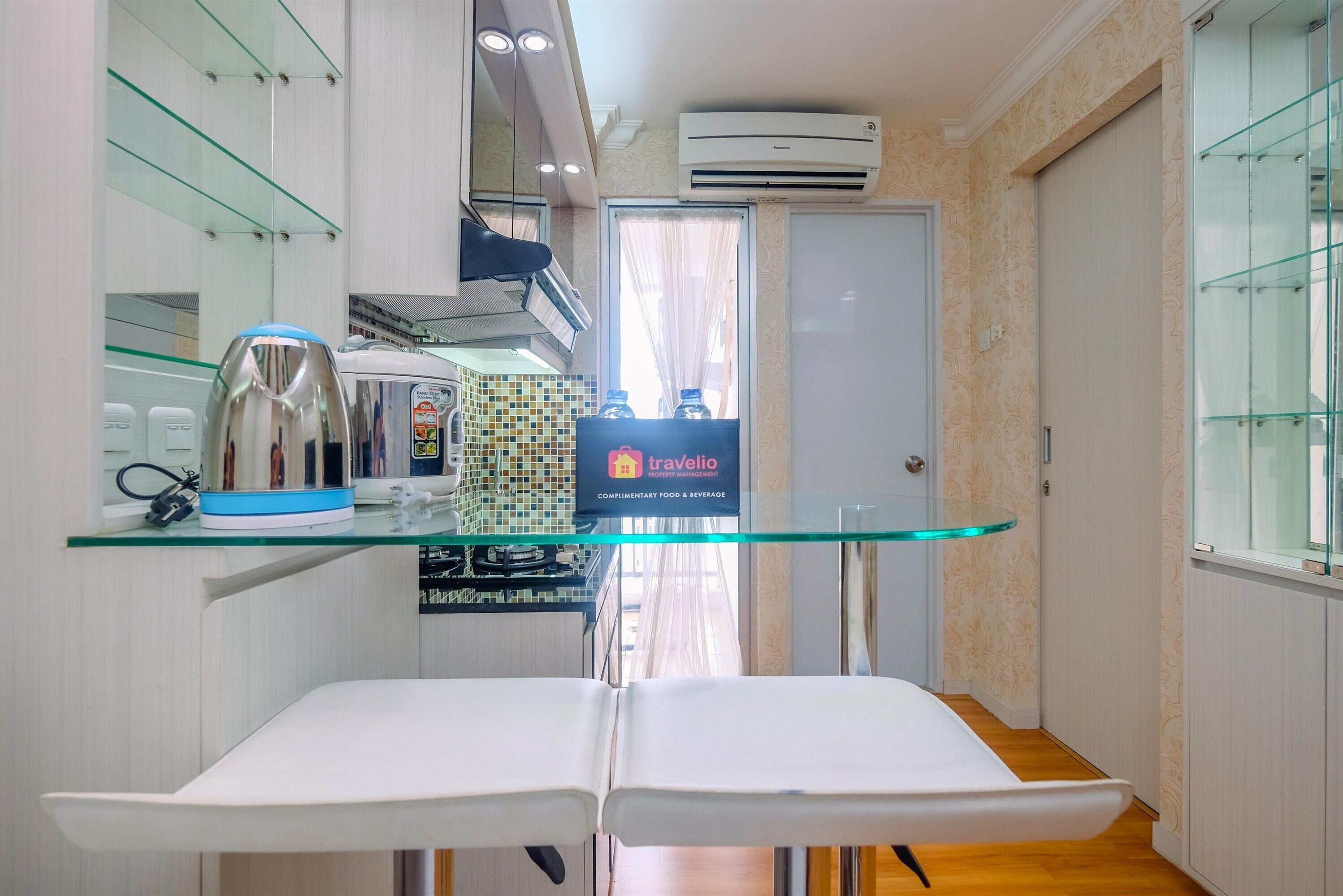 A modern kitchen with a glass shelf, a coffee machine, and a travelio sign.