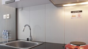 A modern bathroom with a stainless steel sink, a red electric toothbrush, and a wall-mounted towel rack.