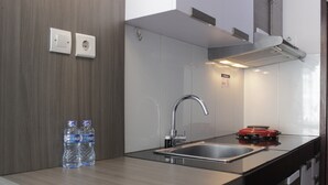 A modern kitchen with a stainless steel sink, a red stove, and two water bottles on the counter.