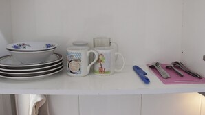 A kitchen counter with stacked plates, a mug, a jar, and utensils.