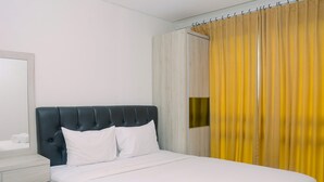 Quarto de hotel com cama, mesa de cabeceira, espelho e janela com cortinas amarelas.