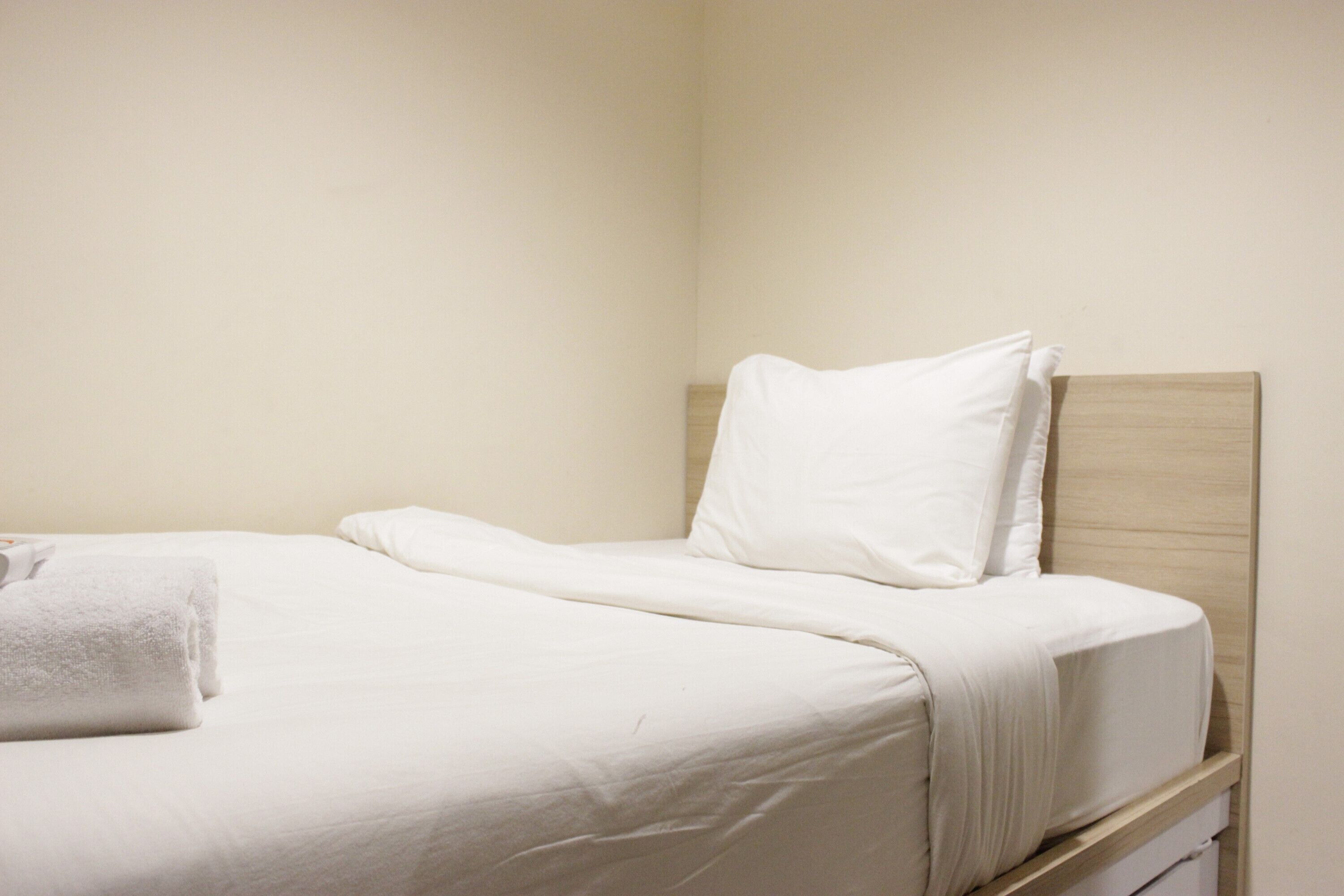 Un lit bien fait, avec du linge de lit blanc et une serviette blanche pliée sur le côté gauche.