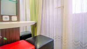 Une salle de bain avec un miroir, deux prises électriques, un tabouret rouge et un tabouret noir.