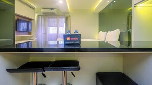 Une chambre d’hôtel moderne équipée d’une télévision à écran plat, d’un minibar, d’un lit et d’une salle de bain avec rideau de douche.