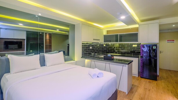 Une chambre d’hôtel moderne équipée d’un lit, d’une petite kitchenette et d’un réfrigérateur.