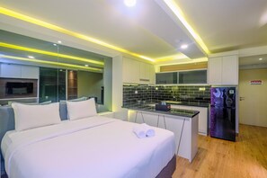Una habitación de hotel moderna con una cama, una kitchenette pequeña y un refrigerador.
