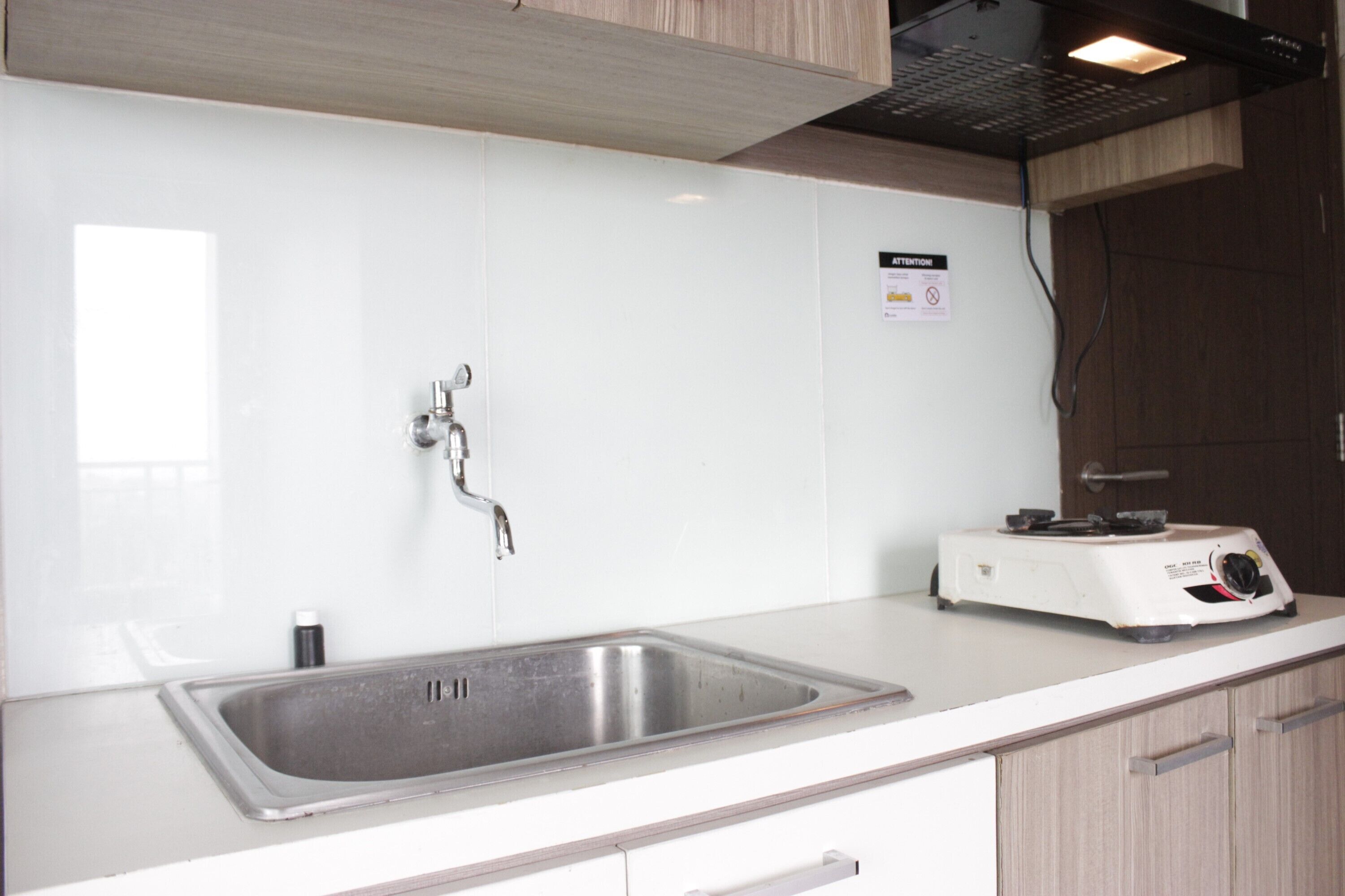A kitchen with a stainless steel sink, a white countertop, and wooden cabinets.