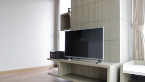 Ein modernes Wohnzimmer mit einem an einer Holzwandkonsole befestigten Flachbildfernseher, einer kleinen Ablage mit einer Schachtel und Holzdielen.
