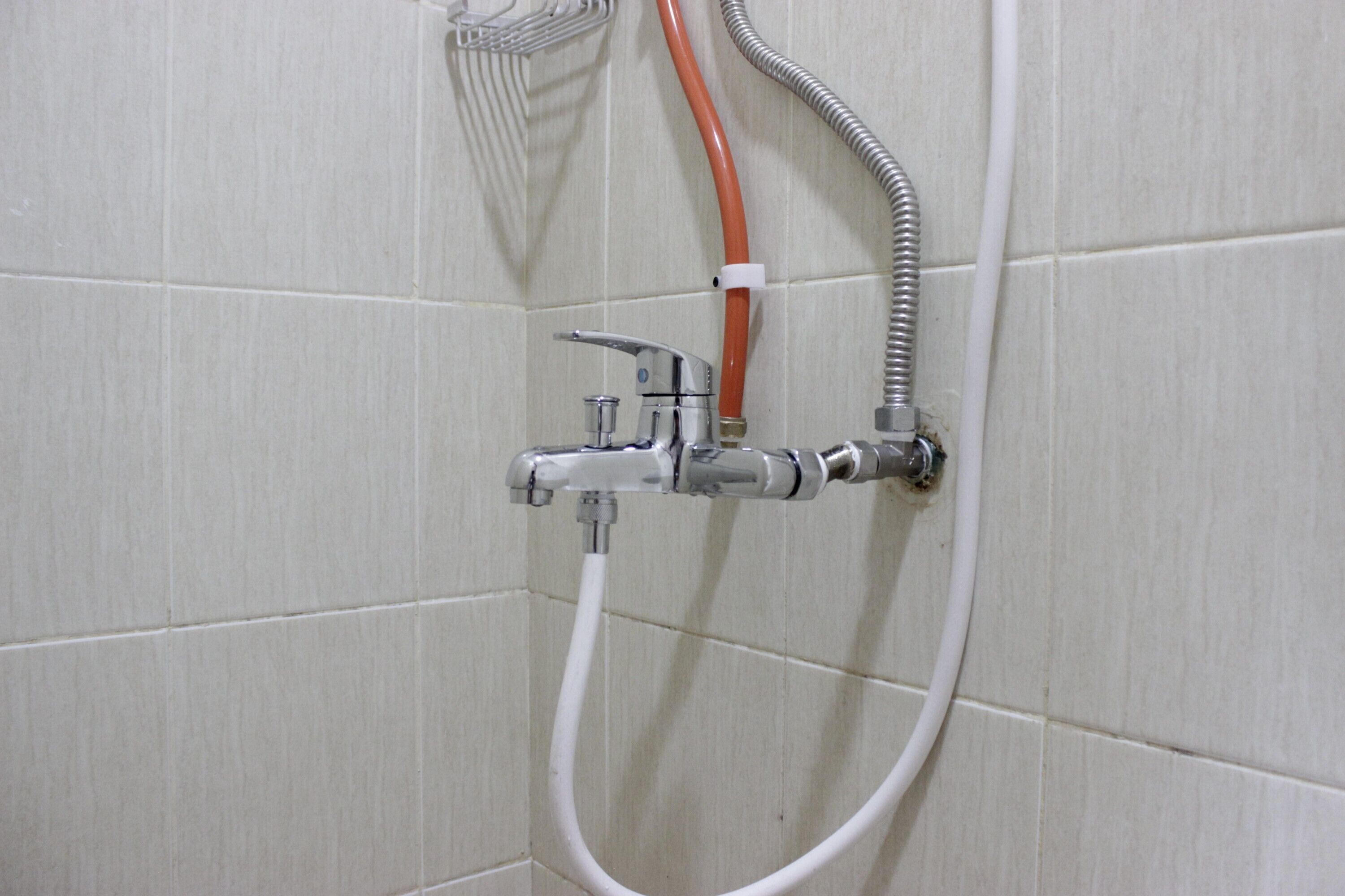 A shower with a chrome faucet and hose.