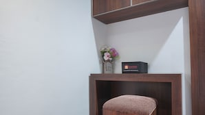 A wooden bench with a cushion, a small wooden table with a vase of flowers and a sign, and a black box with text. - Comfort and Homey Studio Kebagusan City Apartment (Jakarta)