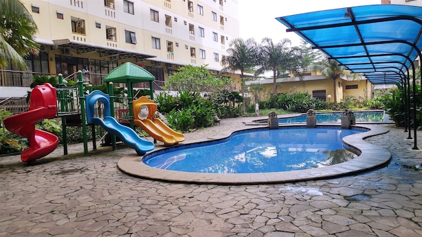 A playground with slides and a small pool, surrounded by a paved area and residential buildings. - Comfort and Homey Studio Kebagusan City Apartment (Jakarta)