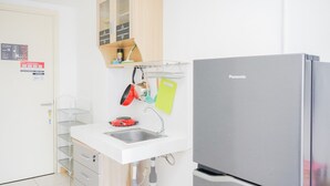 Une cuisine compacte dotée d’un réfrigérateur en acier inoxydable, d’un évier blanc et d’un petit plan de travail.