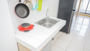 Une cuisine équipée d’un évier en acier inoxydable, d’une cuisinière électrique rouge et d’un réfrigérateur.