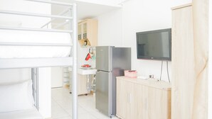 Une cuisine compacte équipée d’un réfrigérateur intégré, d’un four à micro-ondes et d’un meuble en bois.