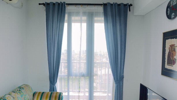 A living room with a sofa, a television, and a large window with curtains.