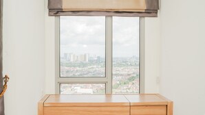 A room with a wooden desk and a large window overlooking a cityscape. - Cozy Living Studio Apartment M-Town Residence (Gading Serpong)