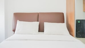A bed with a headboard, two pillows, and a white bedspread. - Cozy Living Studio Apartment M-Town Residence (Gading Serpong)