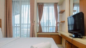 A hotel room with a bed, a TV, and curtains.