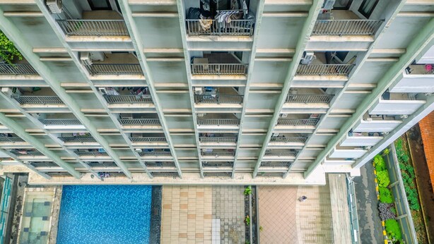 A high-rise building with multiple balconies, a swimming pool, and a landscaped area with plants. - Comfort Studio Tamansari Sudirman Apartment (Jakarta)