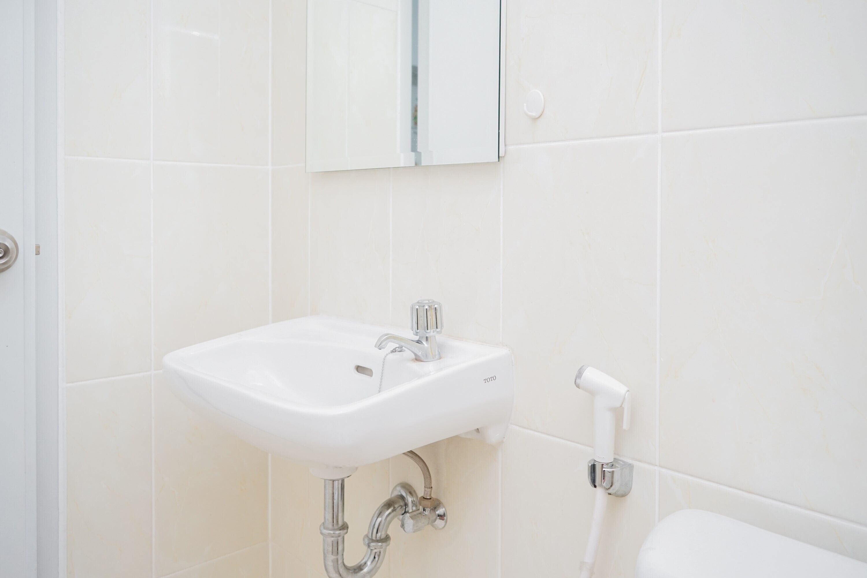 Un baño con un lavamanos blanco, un espejo y un inodoro.