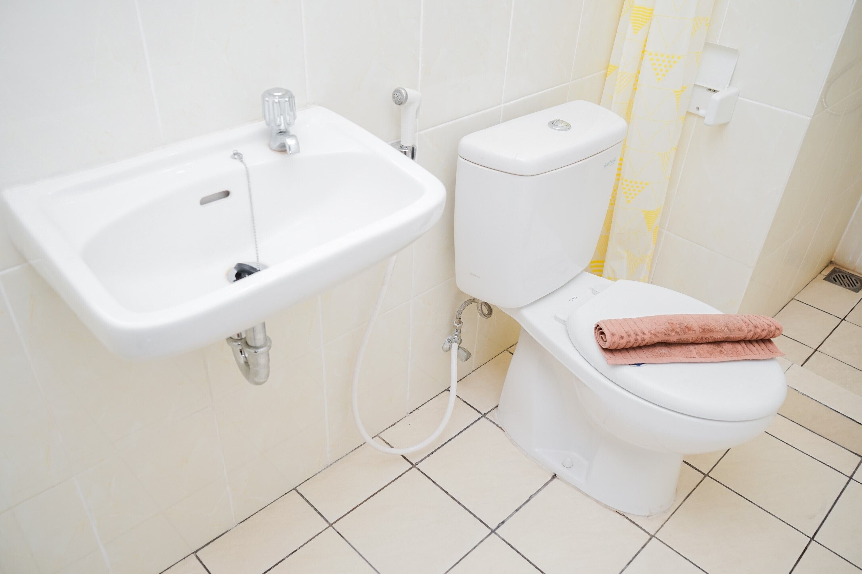 A bathroom with a white sink, toilet, and a towel on the toilet seat.