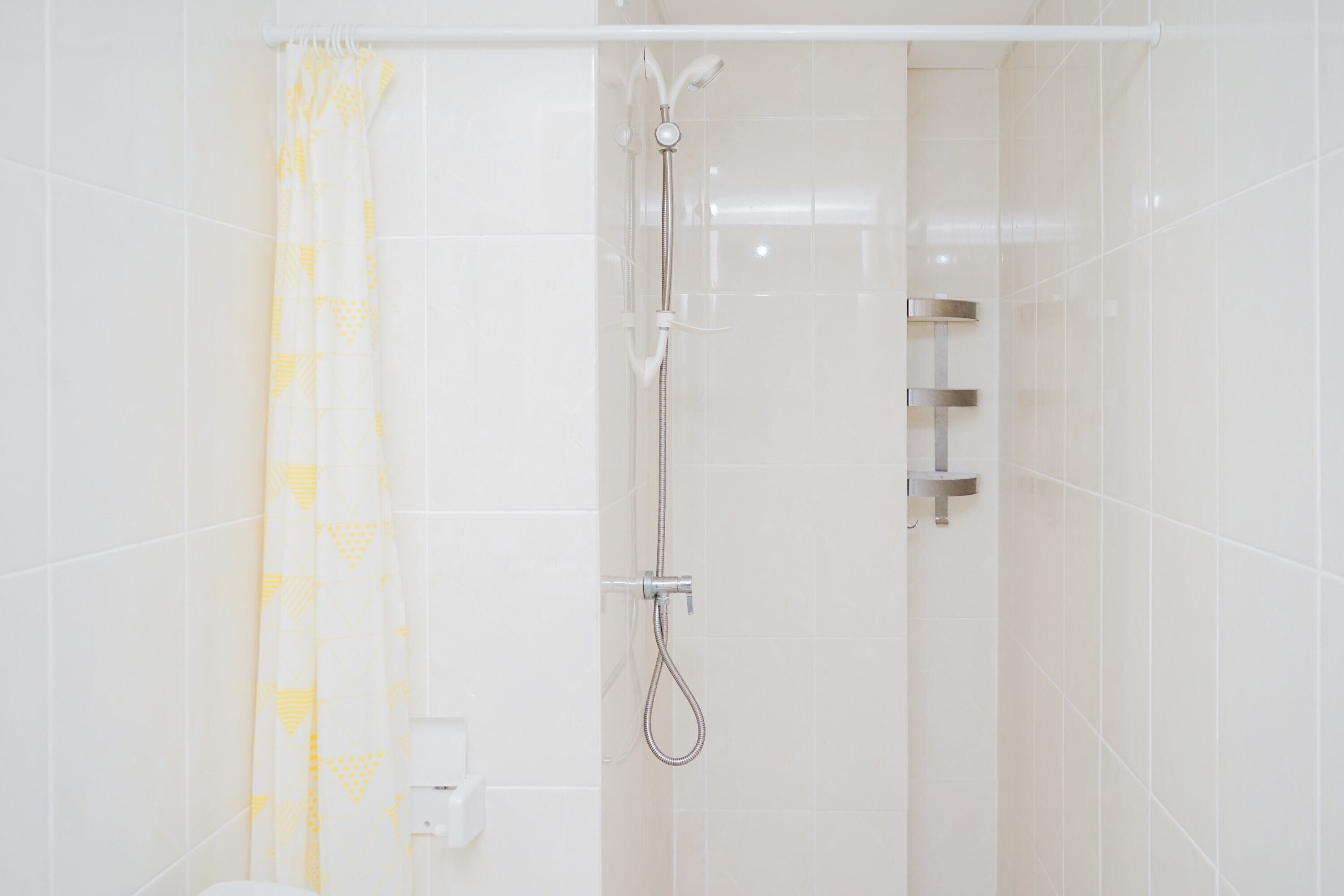 A shower with a handheld showerhead and a wall-mounted faucet.