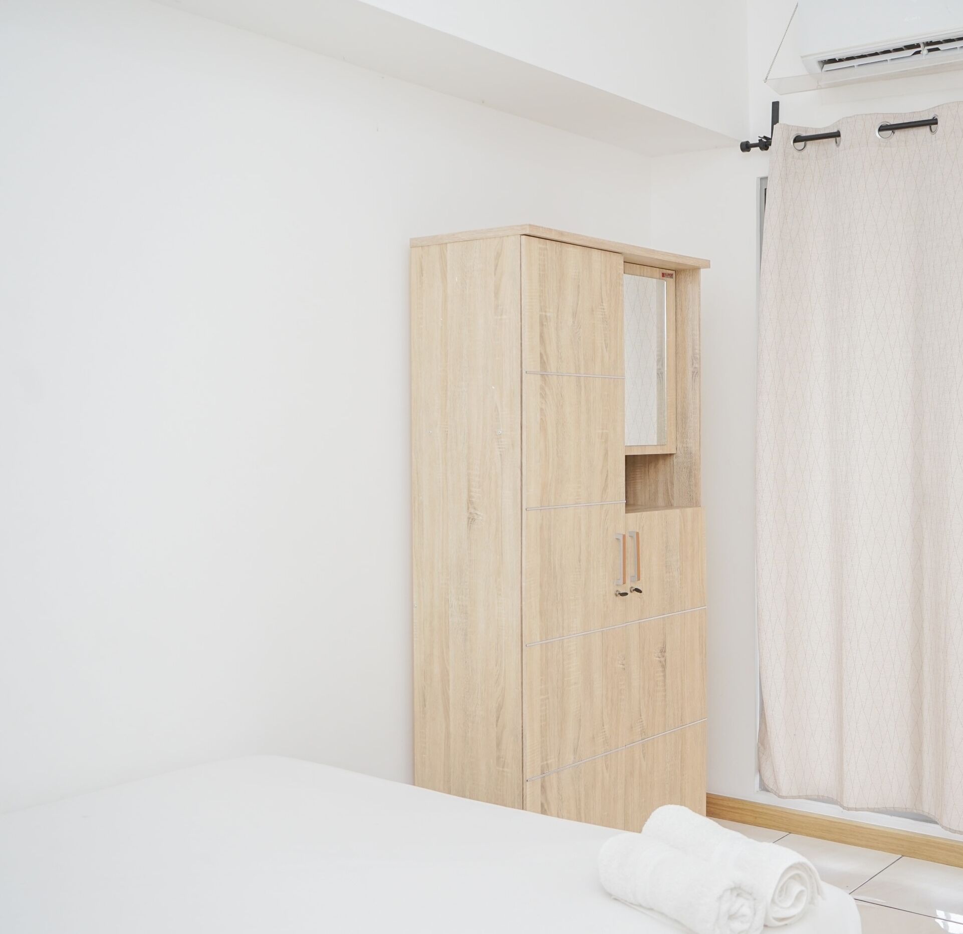 Un dormitorio minimalista con un armario de madera, una cama y una ventana con cortina.