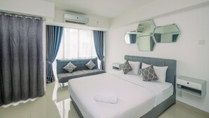 A modern hotel room with a large bed, a seating area, a mirror, and an air conditioning unit. - Brand New Studio Apartment at H Residence (Jakarta)