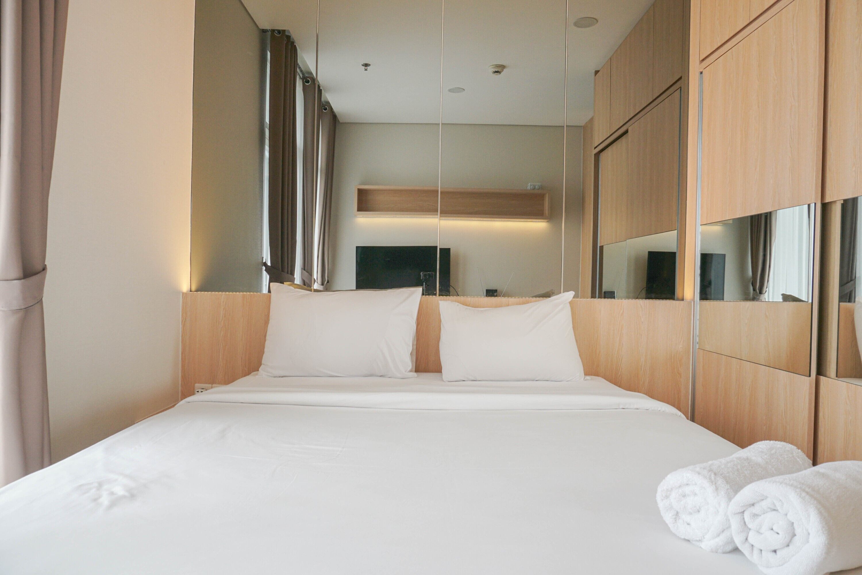 Una habitación de hotel con una cama grande, cabecero de madera y un espejo.